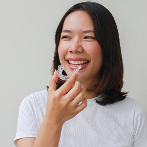 Woman smiling while holding clear aligner