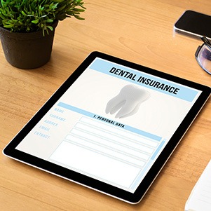 Dental insurance form on tablet next to office supplies