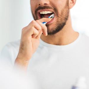 Man in white shirt brushing his teeth