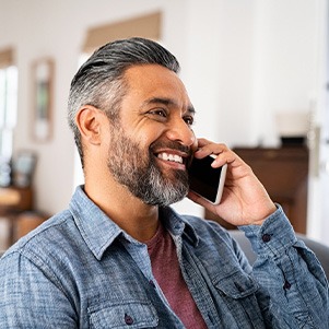 Man smiling while talking on phone at home