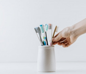 Hand reaches for toothbrush in holder