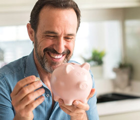 a man smiling and holding onto a piggy bank