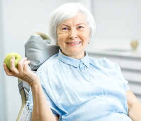 woman in dental chair holding an apple