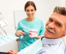 Older man with mustache smiling in dental chair