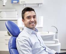 Man smiling in dental chair wearing collared shirt