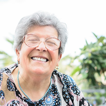 Senior woman with glasses smiling outside