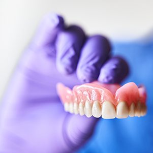 Gloved hand holding a recently made denture