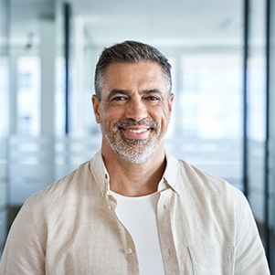 Man in button-up shirt smiling in room with glass walls