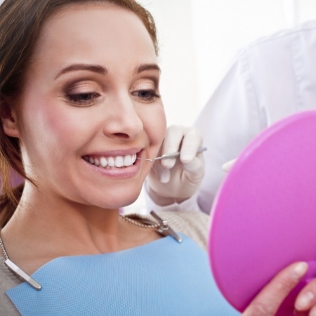 Woman checking her smile in a handheld mirror