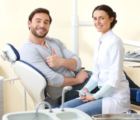 Patient giving thumbs up after successful dental implant salvage