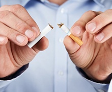 person breaking a cigarette in half