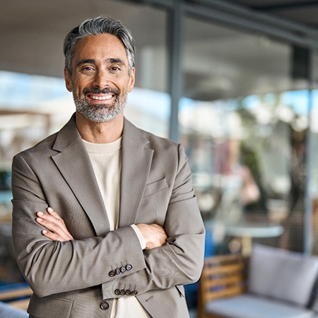 Senior man in suit smiling with arms folded