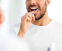 Man brushing his teeth after dental implant surgery in Port Orange