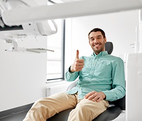 Male dental patient in light green shirt giving thumbs up