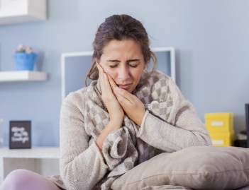 woman holding cheek in pain