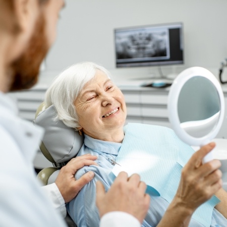 Senior woman checking smile in handheld mirror