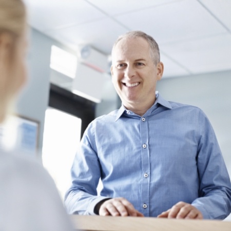 Older man talking to woman at front desk