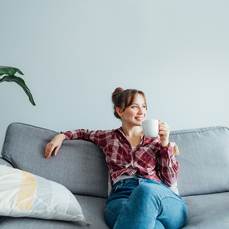 Woman sipping a drink while sitting on her sofa