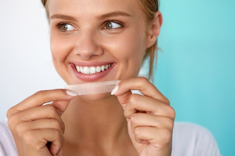 woman using over-the-counter teeth whitening products 