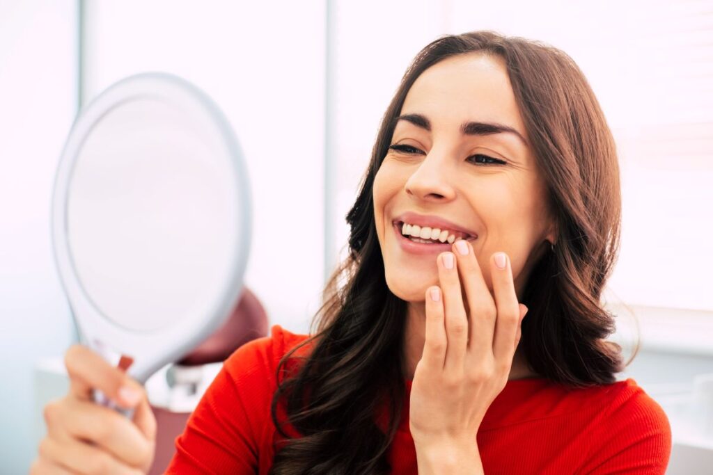 A woman looking at her newly restored smile in the mirror