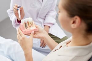 Dentist points to dental implant model held by patient.
