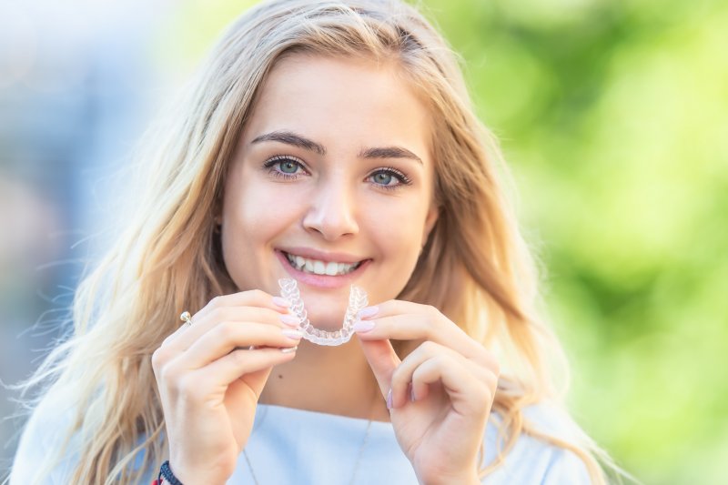 young girl holding Invisalign aligner