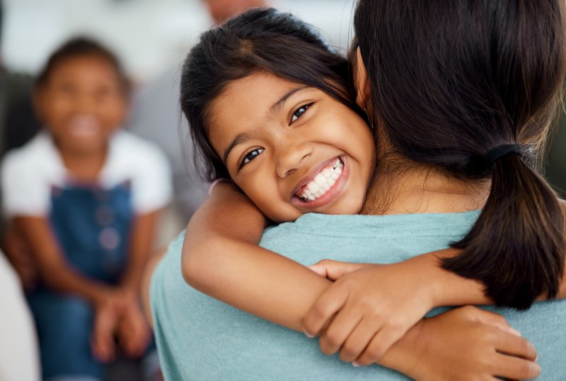 Child smiling with their parent after tooth extraction