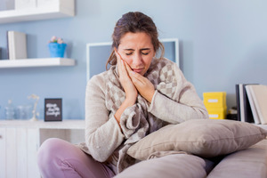 Woman in a light grey shirt with tooth pain