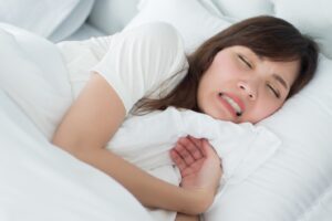Woman grinding her teeth while she sleeps in bed.