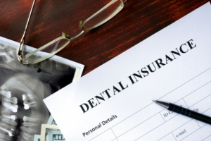 A dental insurance application sitting on a wood desk next to an X-ray 