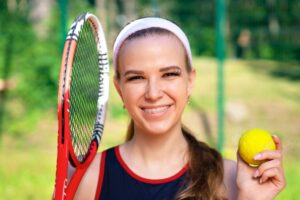 Athlete with braces holding tennis equipment